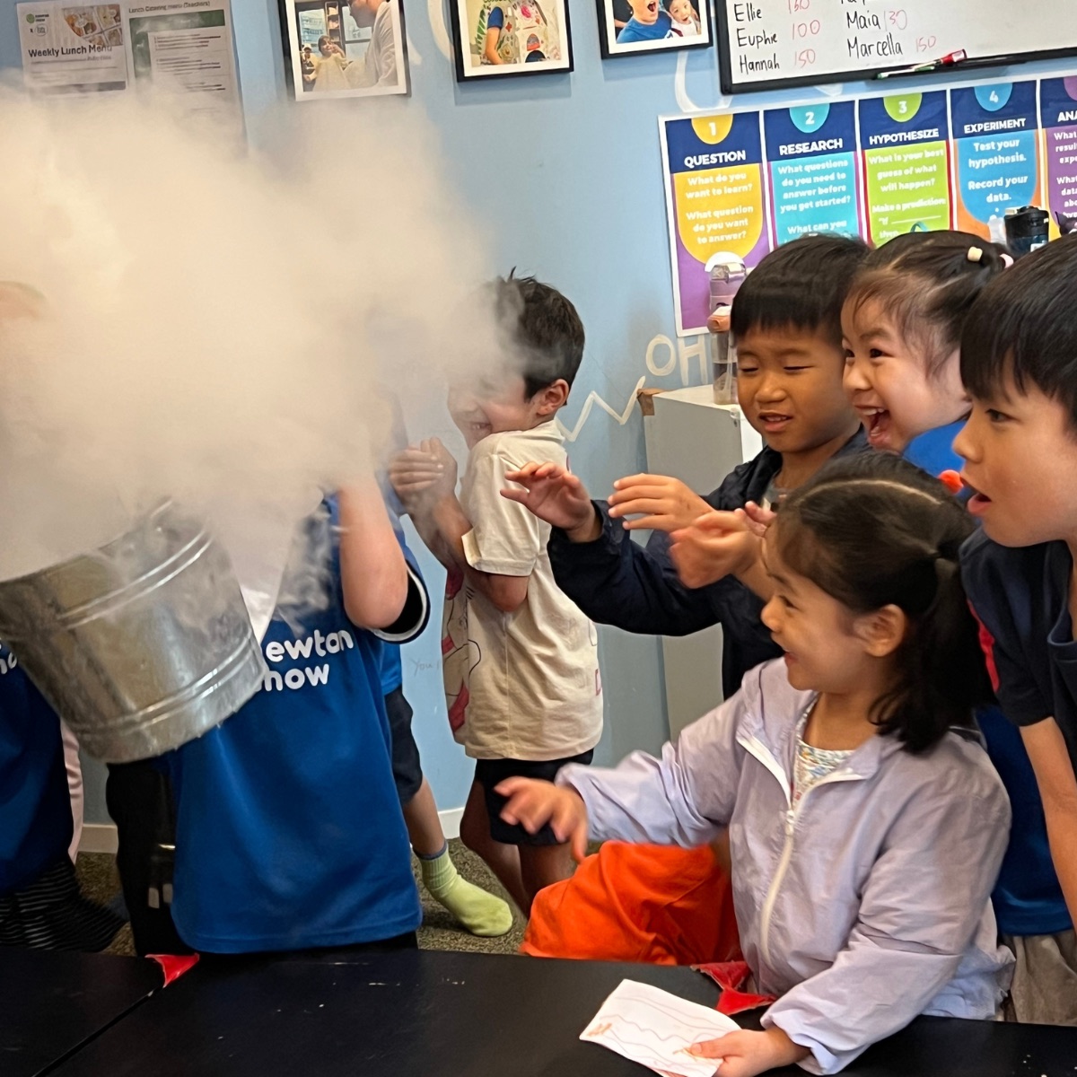 Children reaching into a huge cloud of dry-ice fog at a Newtonshow science camp