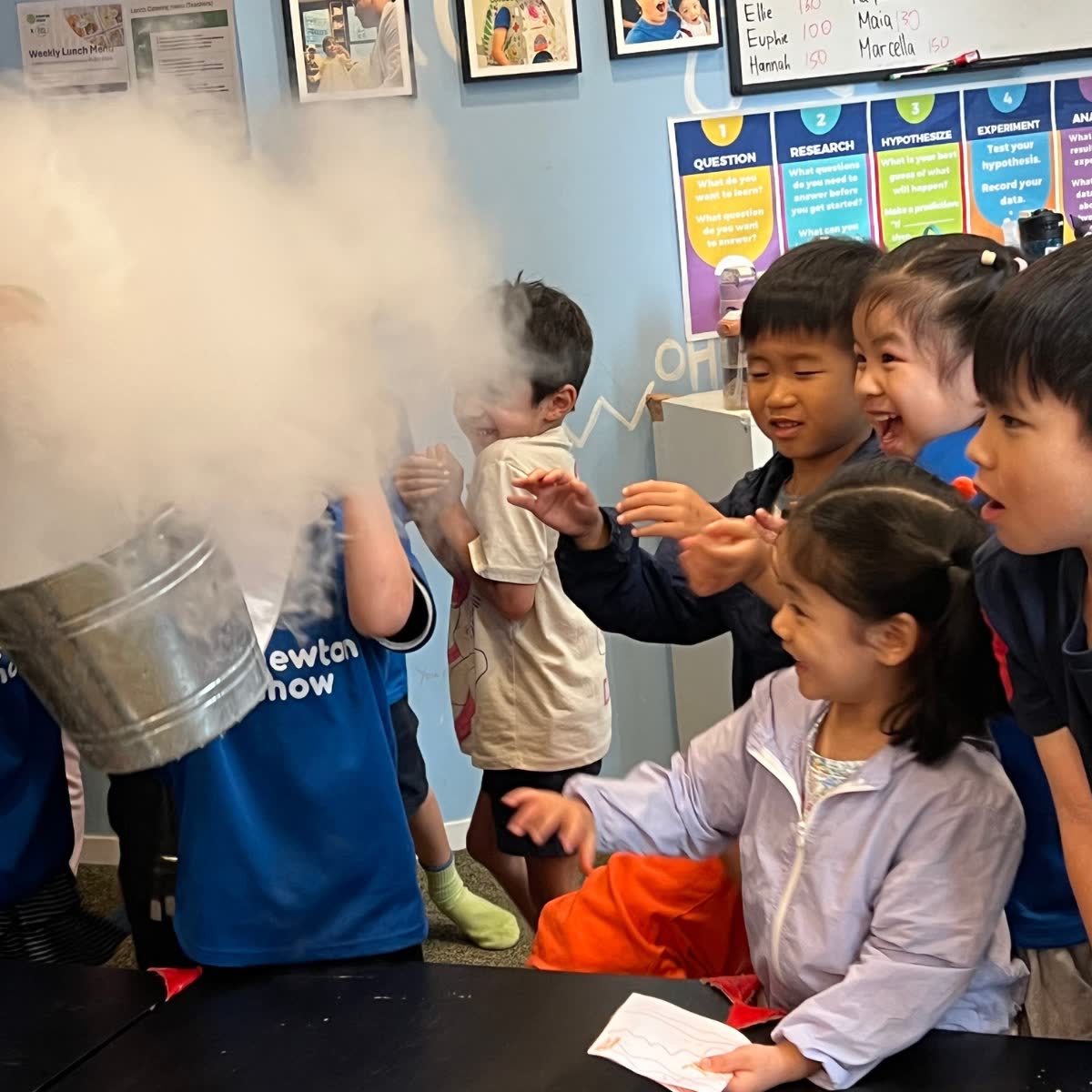 Children reaching into a huge cloud of dry-ice fog at a Newtonshow science camp