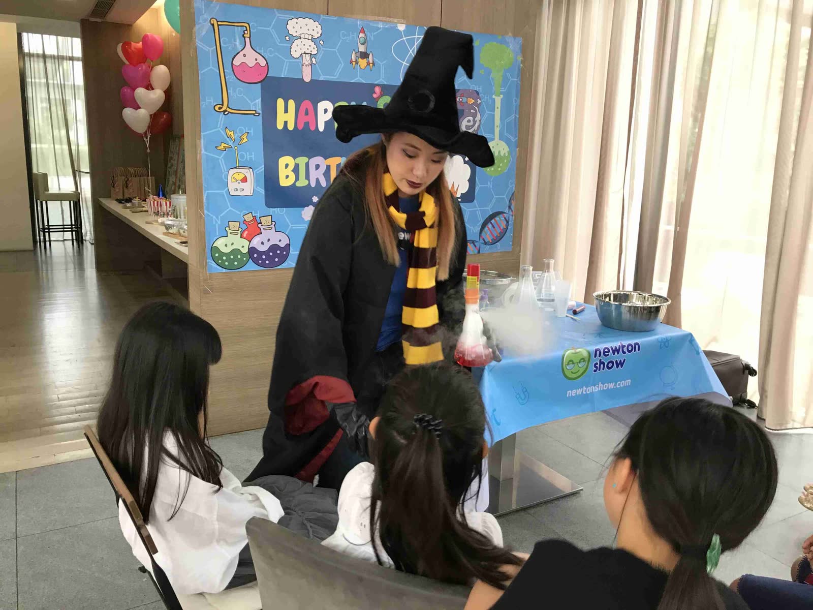 Wizard-costumed host leading a hands-on experiment with young guests at a Newtonshow birthday party