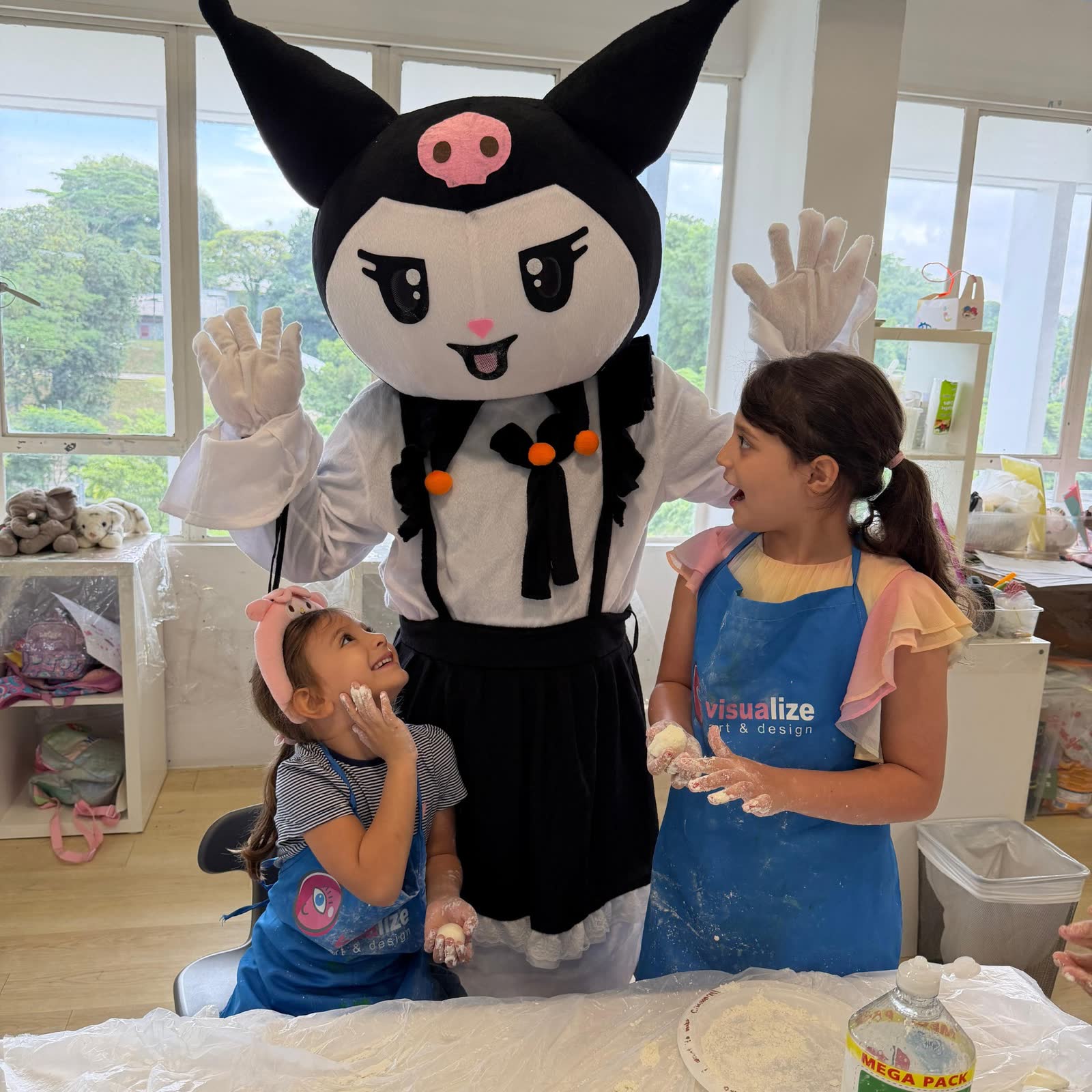 Two girls baking with a kawaii costumed character at a Newtonshow winter camp