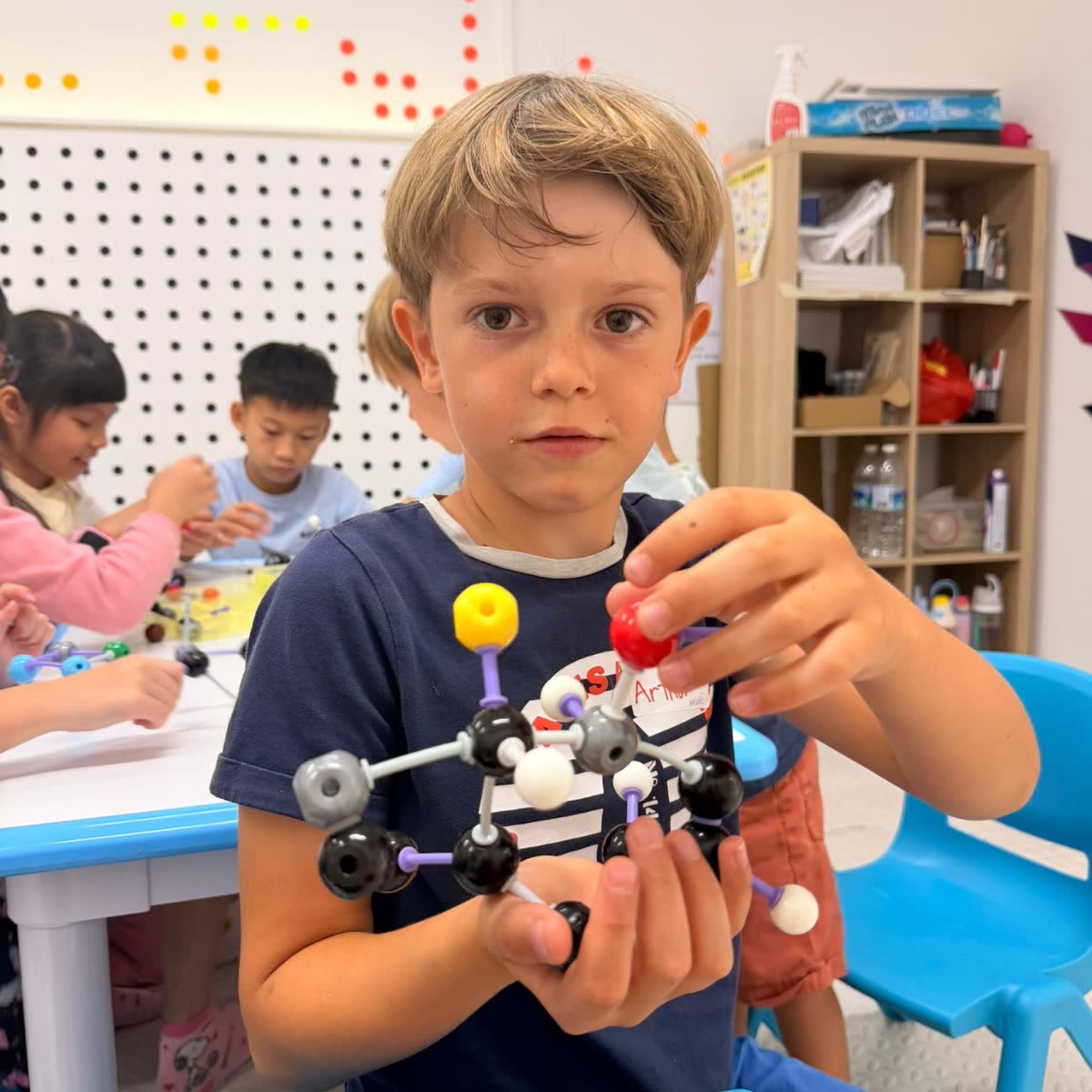 Boy proudly holding the molecular model he built at a Newtonshow science camp