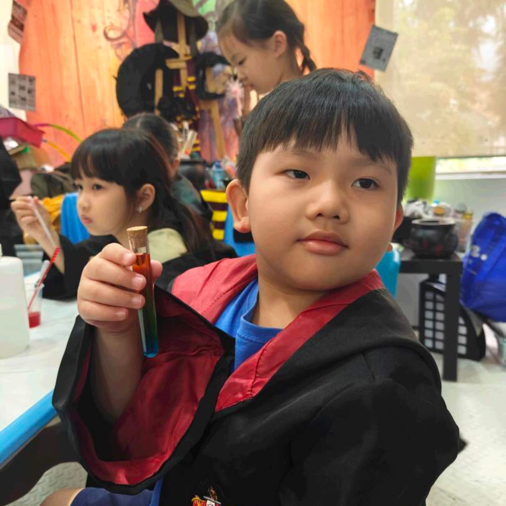 Boy in a wizard robe holding up the red potion he brewed at a Newtonshow birthday party