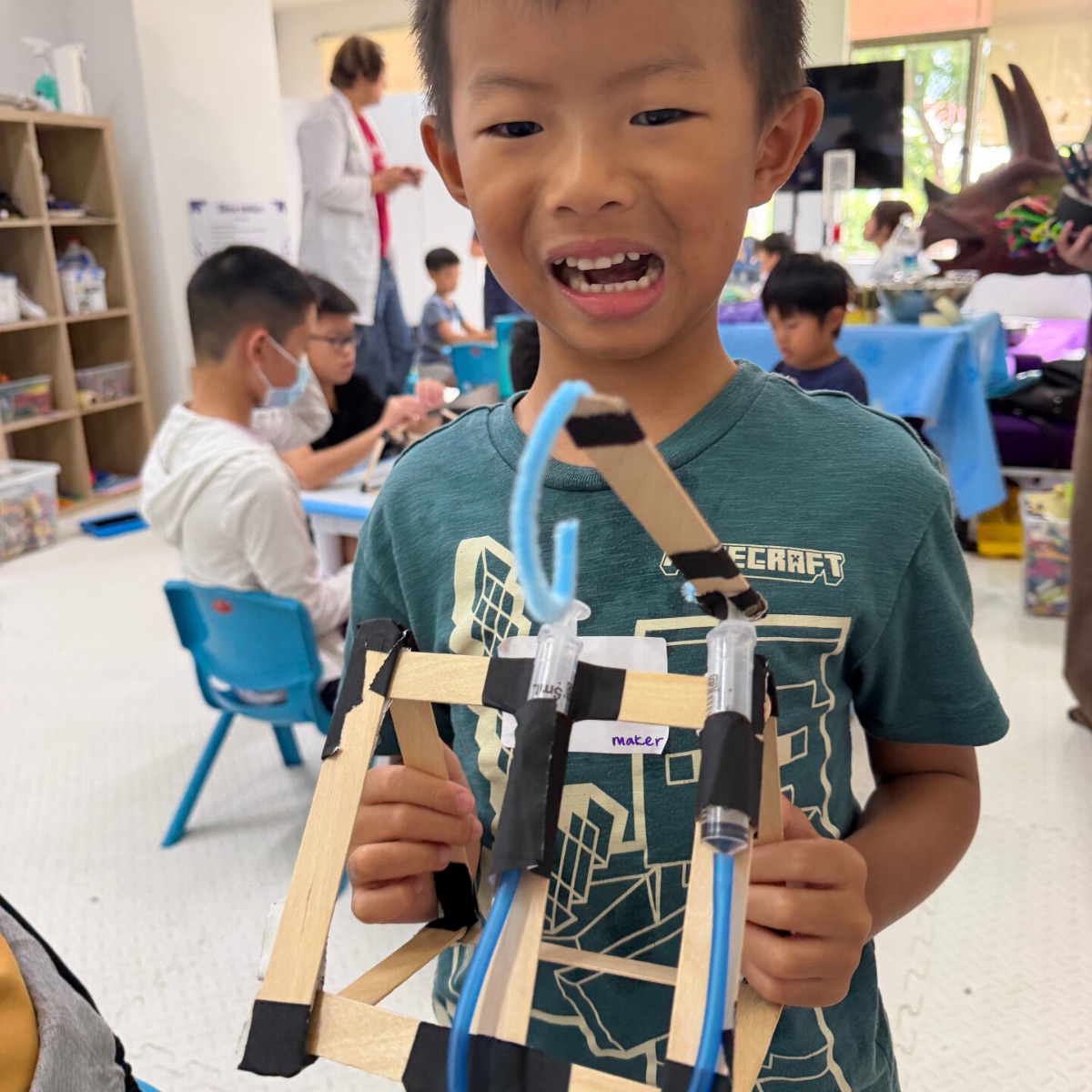 Boy holding the wooden-stick structure he engineered at Newtonshow