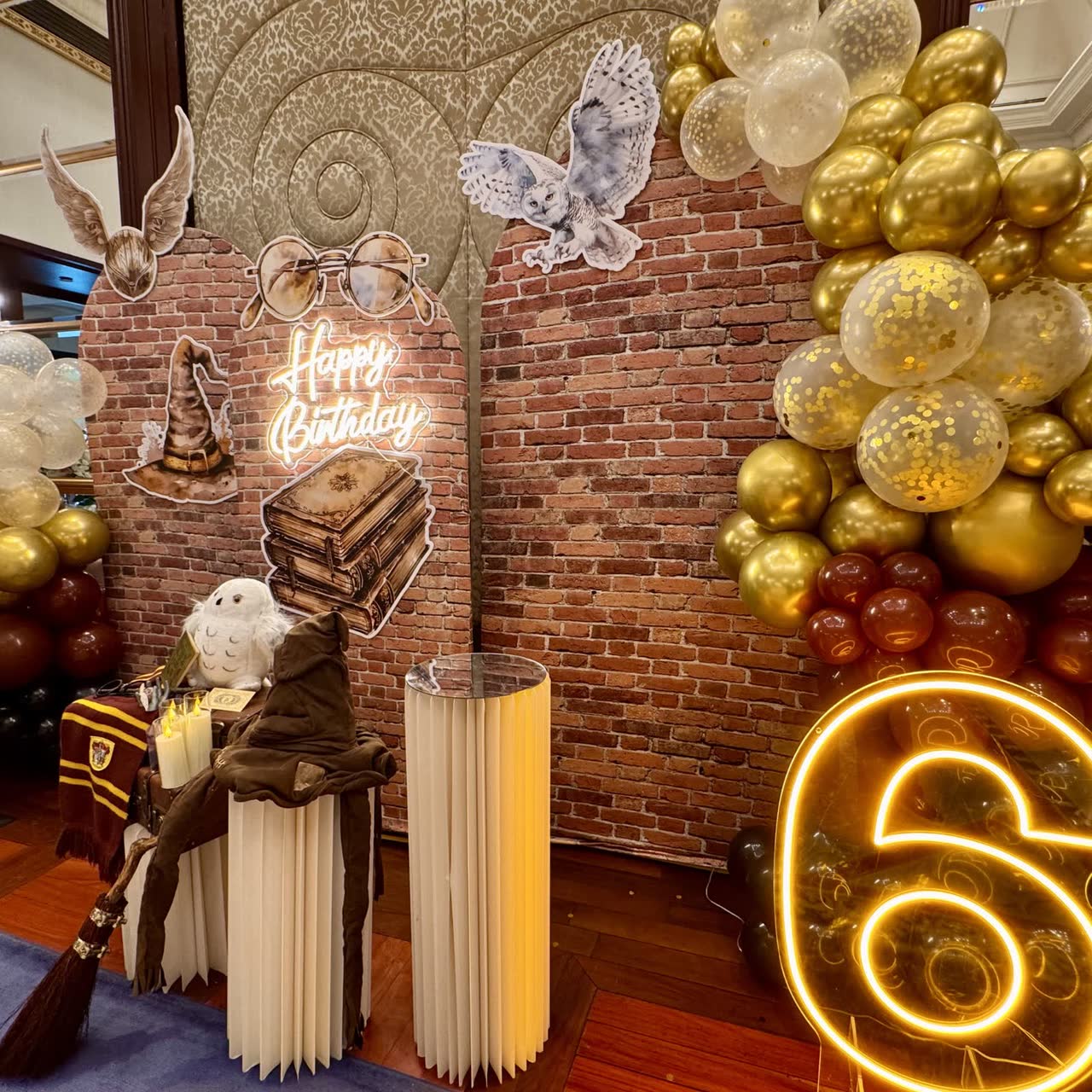 Wizard-themed birthday backdrop with balloons and books at a Newtonshow party